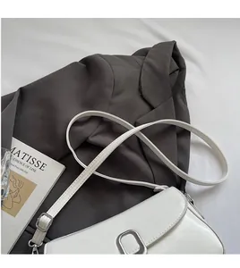Close-up of white leather handbag with silver square buckle on a grey suit background