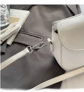 Detailed close-up of glossy white patent leather bag with silver metal hardware