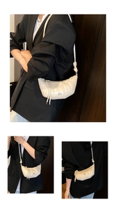 Detail of off-white pleated croissant bag featuring vertical quilting and thin strap