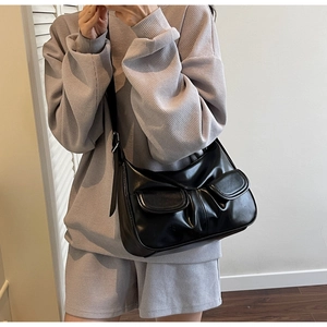 Detail view of the black leather hobo bag featuring two front pockets and adjustable strap