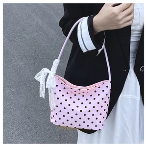 Dettaglio della borsa rosa a pois con un grande fiocco di pizzo bianco e chiusura lampo in metallo