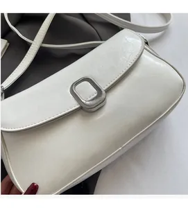 Detail of white rectangle shoulder bag with silver metal buckle and cracked texture