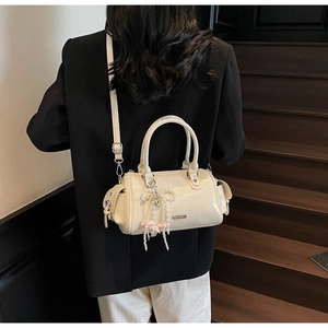 Dettaglio della borsa Boston crema con fiocco di perle e tracolla indossata dalla modella