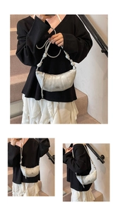 Detail of silver crescent bag featuring pleated stitching and decorative knotted strap
