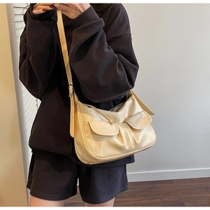 Detail of beige crossbody bag featuring double flap pockets and textured soft faux leather