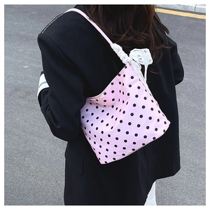 Dettaglio della borsa rosa a pois con fiocco in pizzo bianco sulla tracolla in stile urban