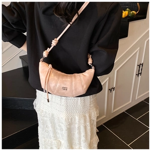 Detail view of pink dumpling bag with shoulder strap knot design and top zipper