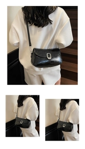 Detail of black glossy crossbody bag with silver oval buckle and thin leather strap
