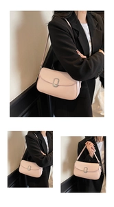 Detail of light pink saddle bag with silver buckle worn over shoulder on a black blazer