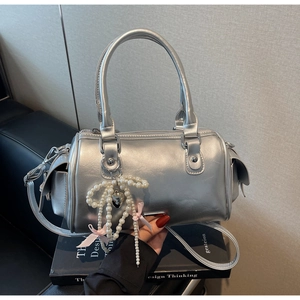 Dettaglio della borsa Boston argento con perle, fiocco rosa e ciondolo a cuore