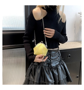 Detail of yellow baseball-shaped mini crossbody bag with metal chain strap