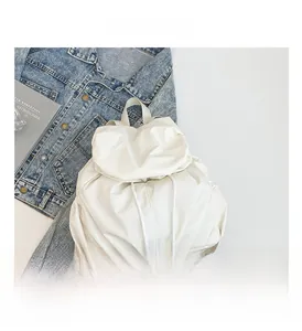 Detalle de mochila blanca con cordón, laterales plisados y textura de cierre de solapa