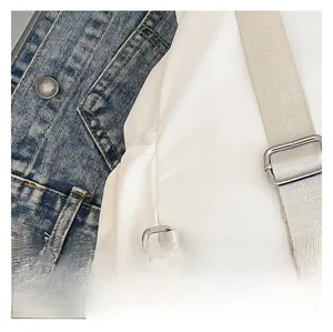 Primer plano de correa de mochila de nailon blanco con hebilla metálica plateada y costura