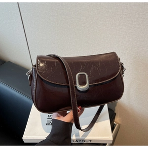 Detail of dark brown glossy leather crossbody bag with silver oval metal buckle and strap