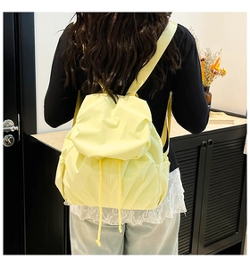 Detail view of a pale yellow drawstring backpack with nylon texture on model