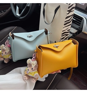 Detail of lychee pattern leather handbags with metal twist locks and plush charms