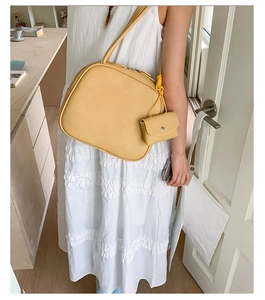 Dettaglio della borsa tote in pelle giallo zenzero con motivo litchi e mini pochette