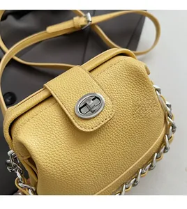Detail of yellow lychee texture handbag with a metal turn-lock and chain strap