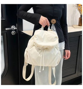 Close-up of off-white backpack with drawstring closure and stylish pleated texture