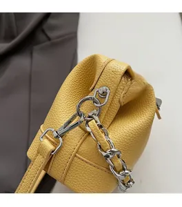 Close-up of premium yellow litchi leather bag with polished silver chain hardware detail
