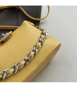 Detail of bright yellow lychee leather handbag with thick silver metal chain and twist lock