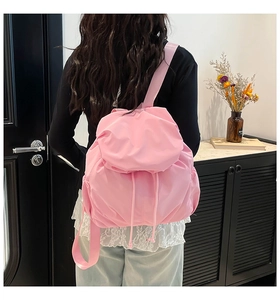 Detail of light pink pleated nylon backpack with drawstring closure shown on a model