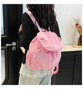 Detail of pink quilted drawstring backpack with ruffled texture and side pocket
