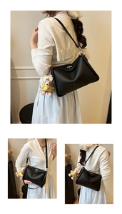 Detail of black lychee grain leather crossbody bag featuring a cute teddy bear charm
