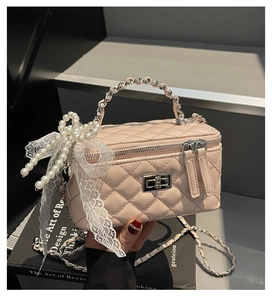 Close-up of pink quilted crossbody bag with pearl bow and white lace details