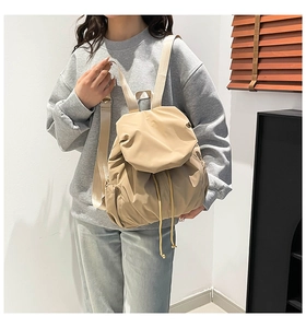 Detalle de mochila caqui con cordón y textura plisada llevada por una modelo en interior