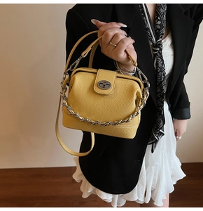 Detail of yellow lychee leather handbag featuring a silver chain and twist lock clasp