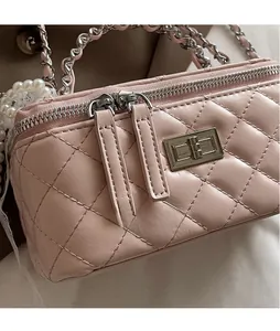 Detailed macro view of pink quilted handbag featuring long leather zipper pull and metal lock