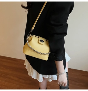 Detail of yellow lychee leather bucket bag with silver chain worn with a black blazer