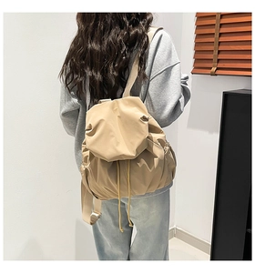 Close-up of the pleated texture and drawstring closure on a beige nylon backpack