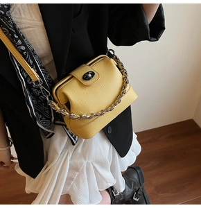 Detail of yellow pebble leather handbag with chunky silver chain and metal turn-lock