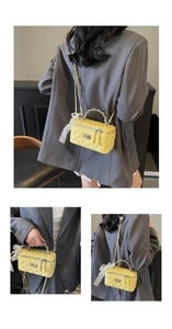 Detail of yellow quilted box bag featuring gold chain strap and lace bow charm