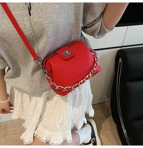 Detail of red crossbody bucket bag featuring silver chain decor and metal clasp