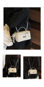 Detail of white quilted crossbody bag with pearl charms and silver rotating metal lock