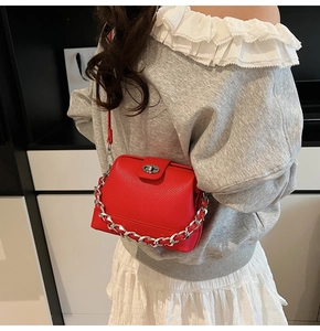 Detail of red pebbled leather crossbody bucket bag with silver twist lock and chain strap