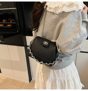 Detail of black lychee grain leather bucket bag with silver chain and turn-lock