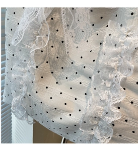 Détail d'un sac cabas beige à pois avec de délicats volants en dentelle blanche et texture