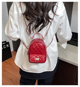 Close-up of red patent leather quilted mini backpack with chain strap on model