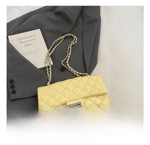 Detail view of yellow quilted leather bag with silver twist lock and chain strap