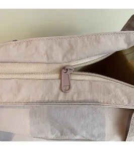 Macro view of a smooth zipper closure on a light beige minimalist tote bag design