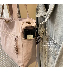 Detail of light pink nylon tote featuring a hidden side zipper pocket for easy storage