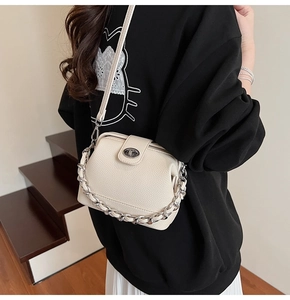 Detail of cream white pebbled leather bag with silver chain strap and rotary buckle