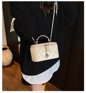 Detail of studded quilted cream crossbody bag with silver rose pendant and chain strap
