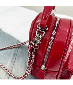 Close-up of red quilted leather handbag with silver metallic zipper and chain strap detail