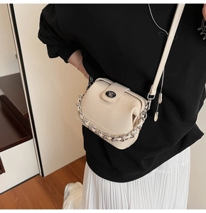 Close-up of cream leather bucket bag with silver metal lock and chain handle detail