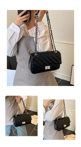 Detail of black quilted leather shoulder bag featuring silver chain strap and metal lock